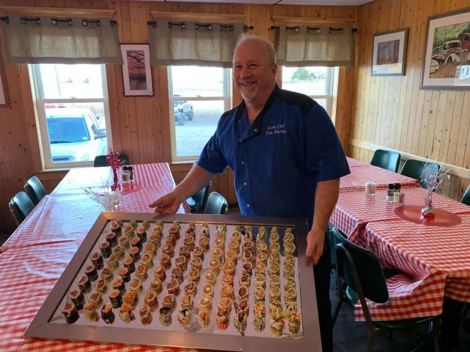 SushiDon Murray holding a large sushi tray at Oyster Creek